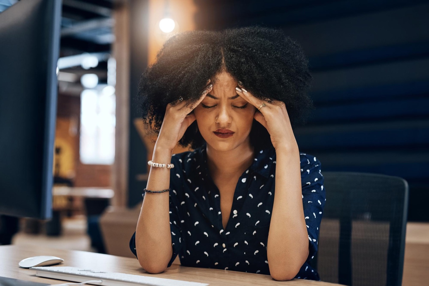 A woman holding her head in frustration while going over her finances
